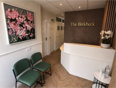 The Birkbeck reception in Sidcup — green chairs, curved white desk and gold lettering
